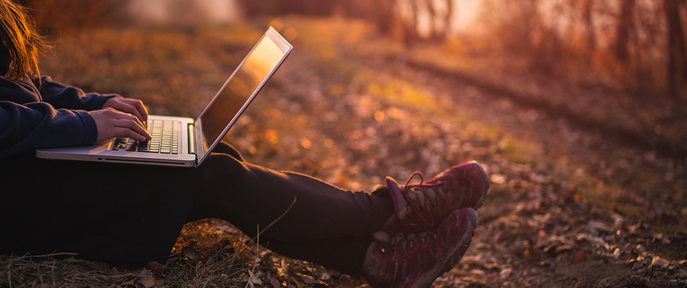 Person using laptop outdoors on trail